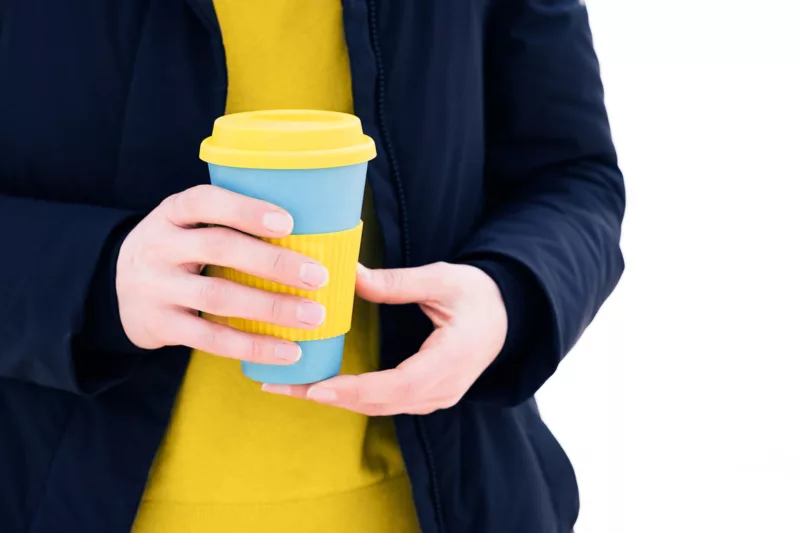 Mensch hält einen wiederverwendbaren To-Go-Becher in den Händen