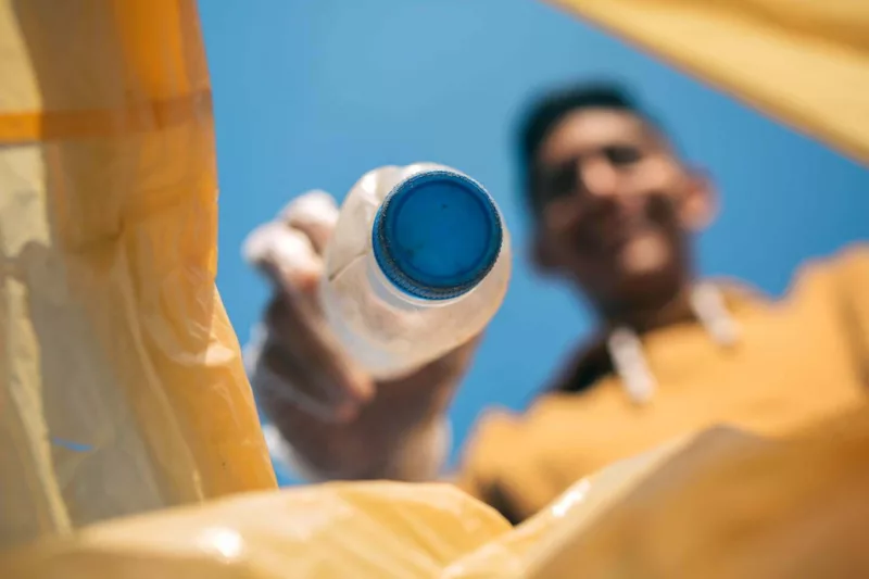 Das passiert mit dem Müll aus der Gelben Tonne 1 Mann hält Plastikflasche in die Gelbe Tonne
