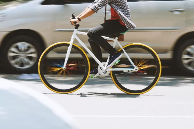 Fahrrad fährt eng neben Auto auf der Straße